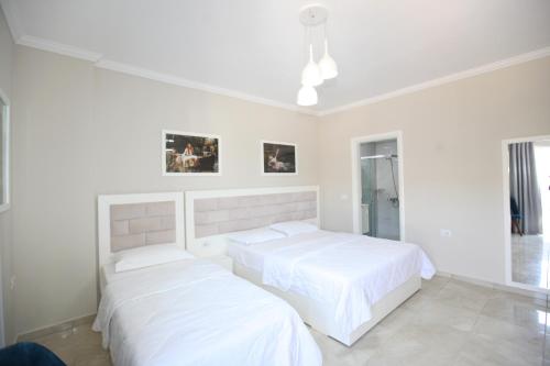 two beds in a bedroom with white walls at Hotel Mare in Ksamil