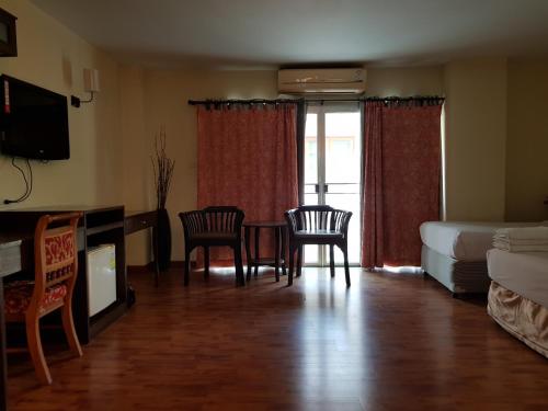a living room with a table and chairs and a bedroom at Pangviman Place Resotel SHA Plus in Chiang Mai