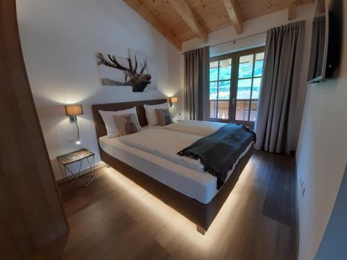 een slaapkamer met een bed en een groot raam bij Hochalmbahnen Chalets Rauris 1-04, Maislaufeldweg 1d in Rauris