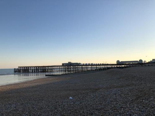 a pier on a beach next to the ocean at Astral Lodge in Hastings