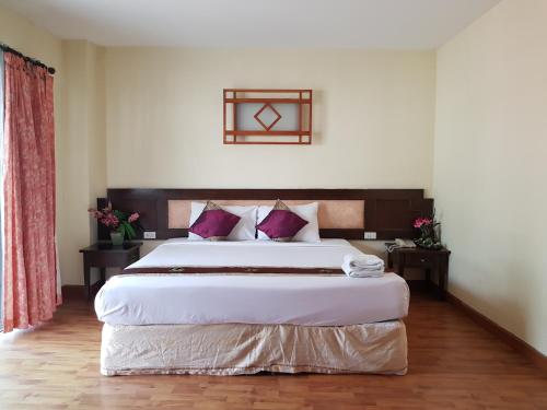 a bedroom with a large white bed with purple pillows at Pangviman Place Resotel SHA Plus in Chiang Mai