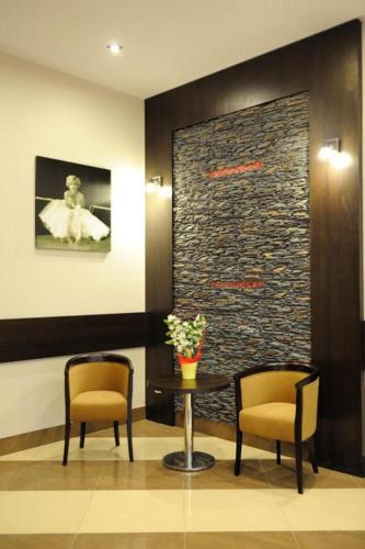 a lobby with two chairs and a table with flowers at Hotel Aquarius Restaurant Wellness Spa in Ciechocinek