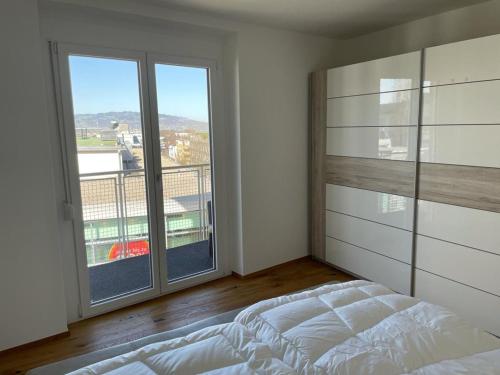 a bedroom with a bed and a large window at Am Marktplatz Exklusives Appartement in Dornbirn