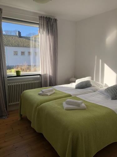 zwei Betten in einem Schlafzimmer mit Fenster und Handtüchern darauf in der Unterkunft Österlengården in Hammenhög