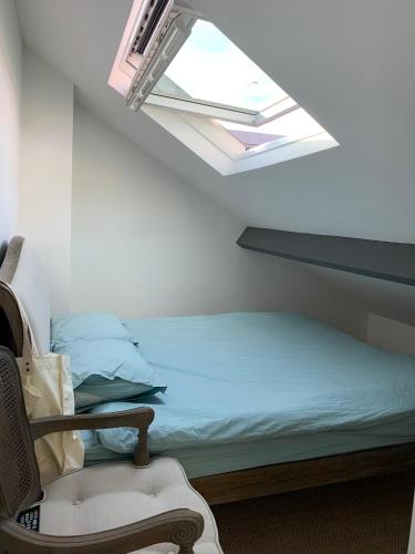 - un lit et une chaise dans une chambre dotée d'une lucarne dans l'établissement Le Touquet-Paris-Plage : appartement avec vue, à Le Touquet-Paris-Plage