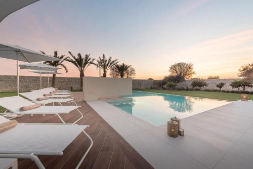 a swimming pool with white lounge chairs and a villa at Villa Ida - IsulaTravel in Frigintini