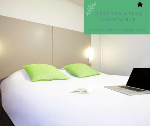 a white bed with green pillows and a laptop on it at Campanile Saint-Etienne Est- Saint-Chamond in Saint-Chamond