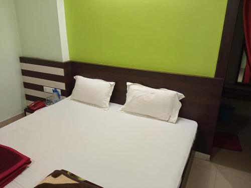 een bed met twee witte kussens en een groene muur bij Hotel Viraat Inn in Gaya