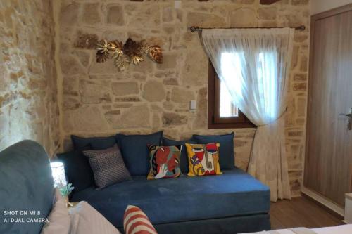 a blue couch in a room with a stone wall at Stonehouse Olivelia - Afrathias Beach in Tympáki
