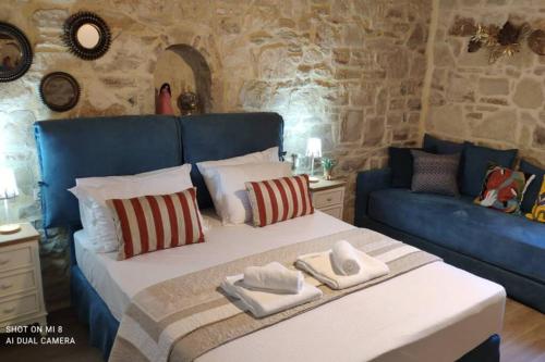 a bedroom with a large bed with a blue couch at Stonehouse Olivelia - Afrathias Beach in Tympáki