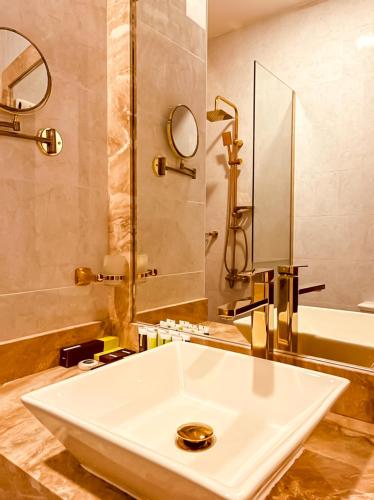 a bathroom with a white sink and a bath tub at Holiday Al Khaleej Hotel in Al Khobar