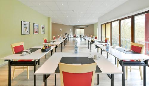 a cafeteria with tables and chairs and windows at City Hotel Meckenheim in Meckenheim