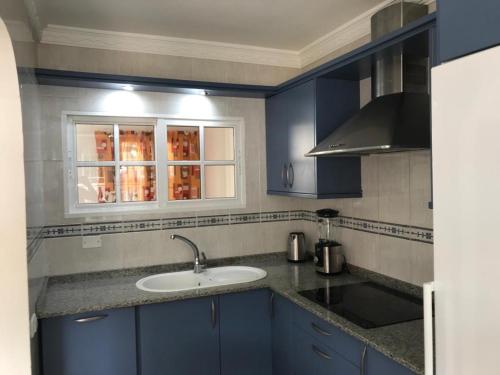 eine blaue Küche mit einem Waschbecken und einem Fenster in der Unterkunft Bungalow Isla Margarita in Puerto Rico de Gran Canaria