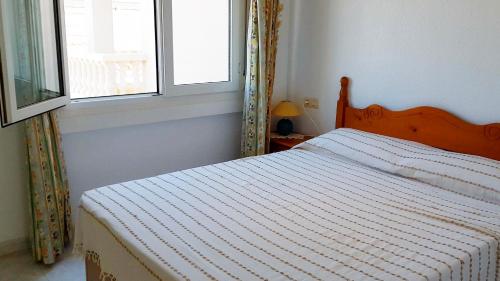 a bed in a bedroom with a window and a bedspread at Atico con vistas al mar Primera línea Cala Montero - ALBERT VILLAS Alcossebre in Alcossebre