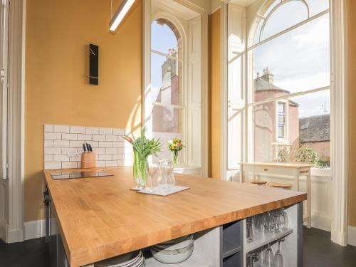 a kitchen with a wooden island in a room with windows at Ne Nimium in Tain