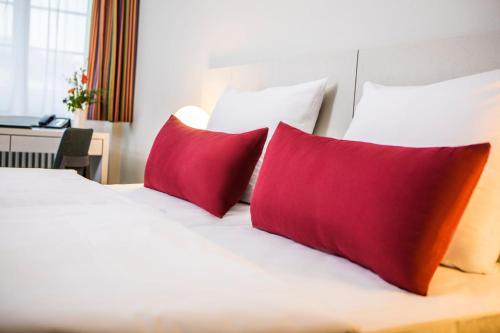 a bed with red and orange pillows on it at Erbacher Hof, Bistum Mainz in Mainz