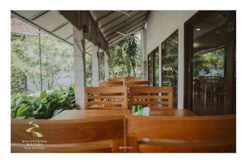a row of wooden tables and chairs in a restaurant at Whispering Waters in Malayāttūr