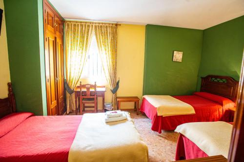 a bedroom with two beds and a table and a window at Hotel Arunda II in Ronda
