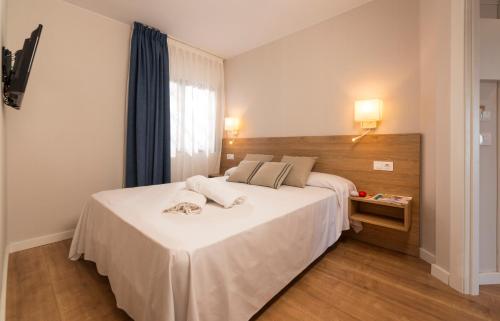 Un dormitorio con una gran cama blanca y una ventana en Apartamentos Guitart, en Lloret de Mar