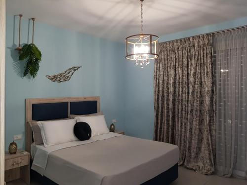 a bedroom with a large white bed with a chandelier at Galazia Thea Apartments in Archangelos