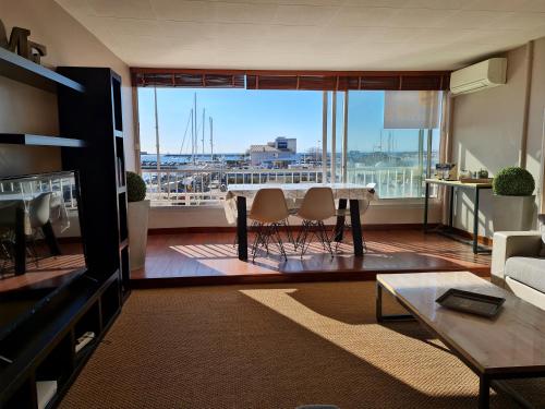 un salon avec une table et une grande fenêtre dans l'établissement Résidence de standing la Pêcherie Spacieux T3 comme un cocon familial vue mer et sur l'avant port Sur le bout du bout de Cap d'Agde seule cap en Occitanie, au Cap d'Agde