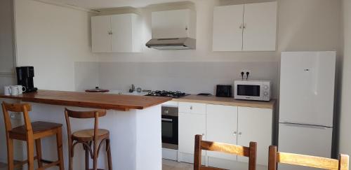 une cuisine avec des placards blancs et un comptoir avec des chaises dans l'établissement Petite maison refaite à neuf dans mas du 19ème siècle, à Arles