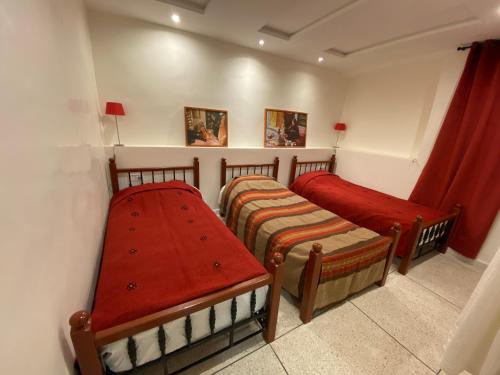 two beds in a small room with red curtains at Appartement coeur de médina in Taroudant