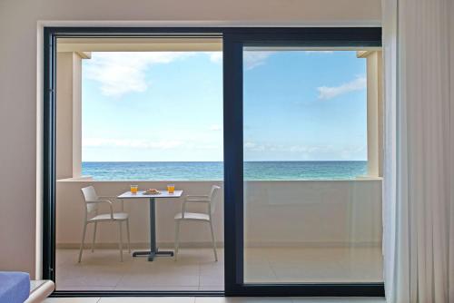 a room with a table and chairs and the ocean at Silver Beach Hotel & Apartments in Gerani Chanion