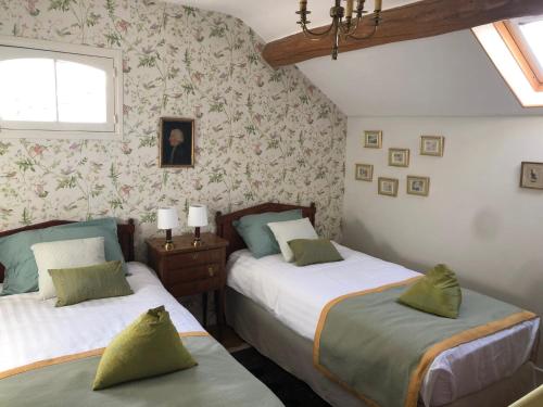 - 2 lits dans une chambre avec papier peint floral dans l'établissement La Maison des trois forêts, à Ermenonville