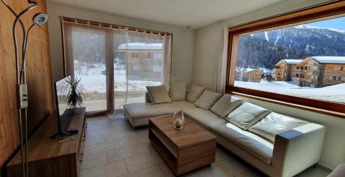 a living room with a couch and a large window at Chalet Breithorn- Perfect for Holiday with Amazing View! in Obergesteln