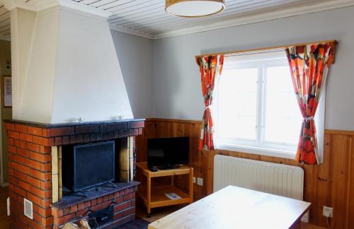 ein Wohnzimmer mit einem Kamin und einem TV in der Unterkunft Ekesberget Stugby stuga 10 in Ekshärad
