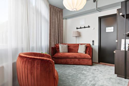 a living room with a red couch and a window at Hotel Giò; BW Signature Collection in Solna