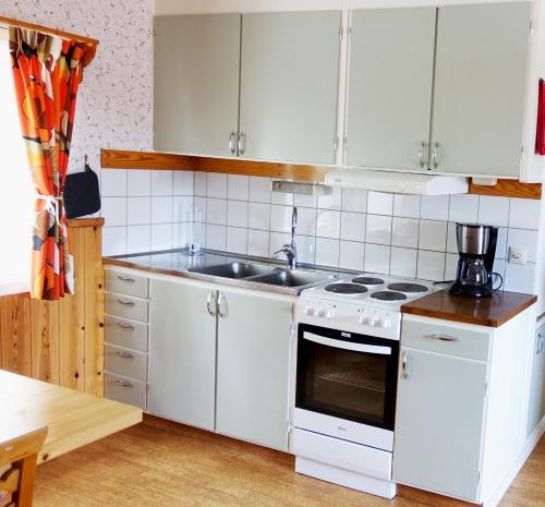 una cucina con armadi bianchi e lavandino di Ekesberget Stugby stuga 10 a Ekshärad