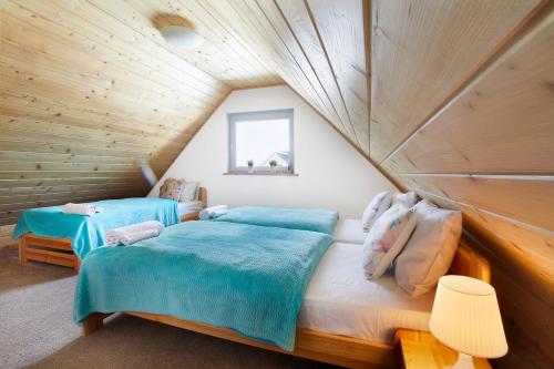 two beds in a room with wooden walls at Apartamenty Liberta in Stare Jabłonki