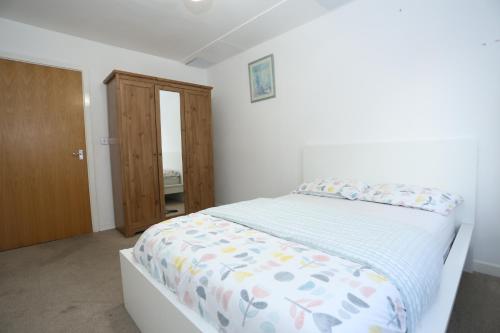 ロンドンにあるBridge House Apartmentの白いベッドルーム(カラフルな掛け布団付きのベッド1台付)