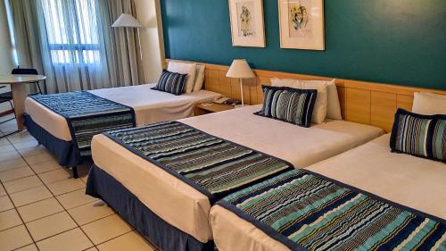 a hotel room with two beds and a table at Reymar Hotel Maceió in Maceió