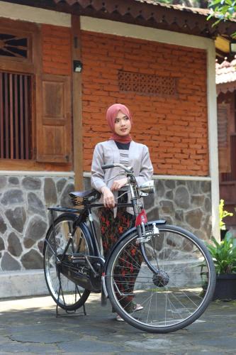a woman is standing next to a bike at Cokro Hinggil - Traditional View in Sleman