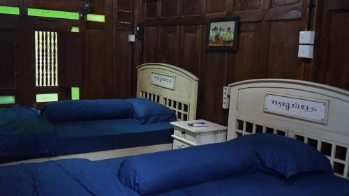 a room with three beds with blue sheets at Cokro Hinggil - Traditional View in Sleman