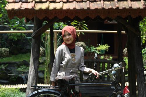 a young girl riding a bike under a roof at Cokro Hinggil - Traditional View in Sleman