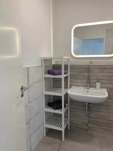 W białej łazience znajduje się umywalka i lustro. w obiekcie FeWo an der Warnow unweit der Ostsee w mieście Rostock