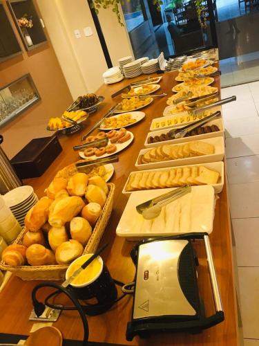 uma longa mesa cheia de pratos de pão e doces em Golden Ville Hotel em Marabá