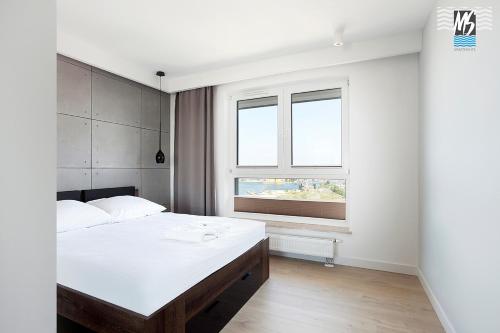 ein Schlafzimmer mit einem großen weißen Bett und einem Fenster in der Unterkunft MS Apartments Sky Tower VIII in Danzig