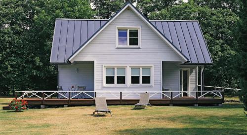 a house with a porch and two chairs in the yard at Niidupuu Holiday Home in Mändjala
