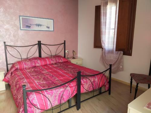 a bedroom with a bed with a red comforter at B&B Colti Di Rosa in Castelsardo