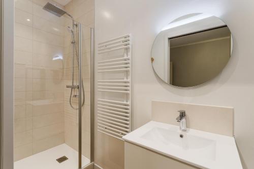 La salle de bains est pourvue d'une douche, d'un lavabo et d'un miroir. dans l'établissement Le Hauturier - appartement de standing avec vue mer, à Saint-Malo