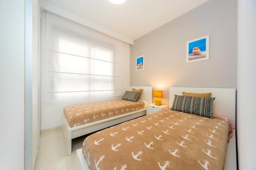 sypialnia z dwoma łóżkami i oknem w obiekcie Luxurious 2 Bedroom Apartment near the beach w mieście La Horadada