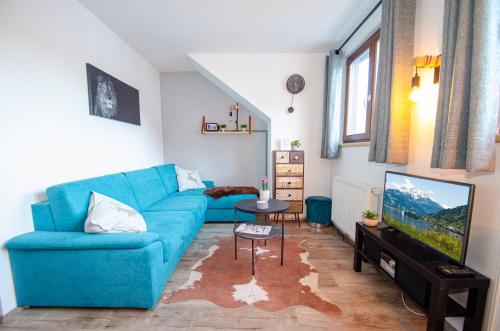 a living room with a blue couch and a tv at Post Residence Apartments by All in One Apartments in Zell am See
