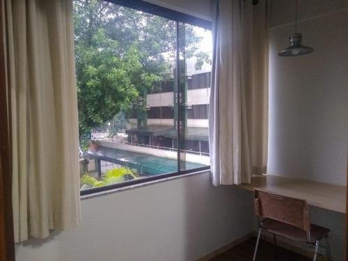 a window with a view of a swimming pool at Harbor Inn Jaraguá in Jaraguá do Sul