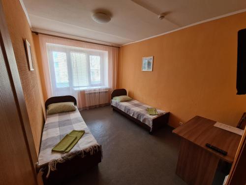 バラショフにあるГостиница Юбилейнаяのベッド2台とテーブルが備わる客室です。