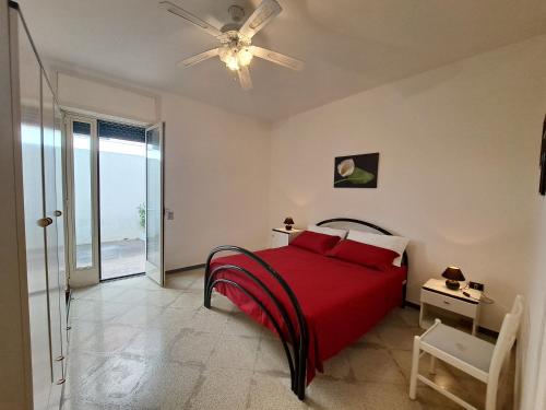 1 dormitorio con cama roja y ventilador de techo en Casa Vittorio a 100m dalla Sabbia, en Lido Marini